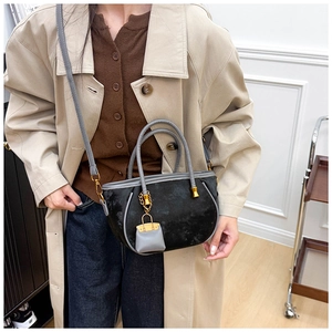 Detail of black velvet bucket bag featuring gray leather trim and a mini bag charm