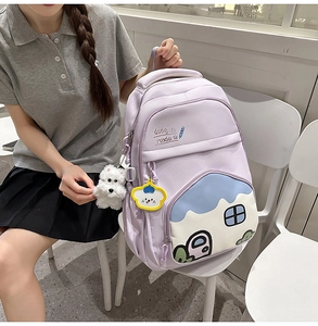 Close-up of light purple canvas backpack featuring a colorful cartoon mountain pocket