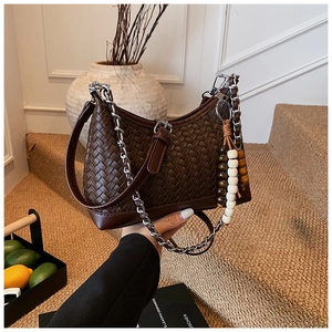 Detail of dark brown woven hobo bag featuring silver chain strap and wood bead ornament