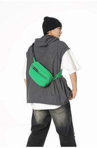 Detailed view of neon green athletic crossbody bag worn by a model on white background