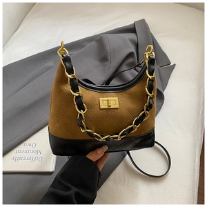 Detail of vintage quilted leather handbag with gold chain strap on a grey suit jacket