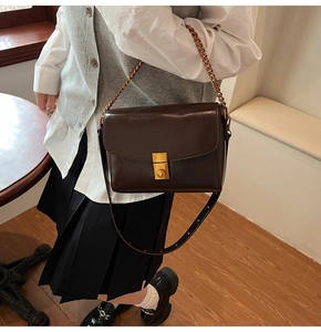 Détail du sac vintage marron foncé avec boucle dorée et bandoulière chaîne