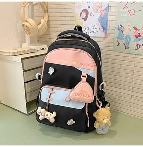 Detail of multi-pocket student backpack with cartoon badges and plush bear pendant accessory