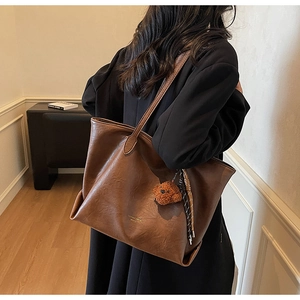 Detailed view of dark brown tote bag with bear charm and fashion trend embossing