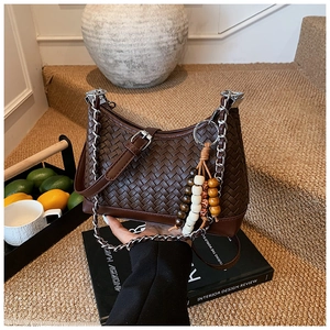Detailed close-up of dark brown woven texture shoulder bag with silver chain and bead tassel