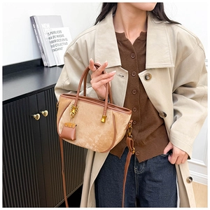 Detail of khaki suede bucket bag with metallic hardware and mini leather pouch charm