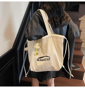 Detailansicht einer beigen Canvas-Tragetasche mit Kordelzug und Logo auf einer Treppe