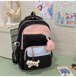Close-up of backpack front pockets featuring a plush cat charm and a pink coin purse accessory