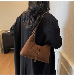 Detailed view of brown suede hobo bag with diagonal stitching and decorative buckle strap