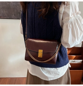 Détail du sac vintage bordeaux avec boucle en métal doré et bandoulière en chaîne