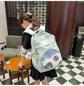 Detail view of mint green backpack with cartoon house pattern and white puppy plush charm
