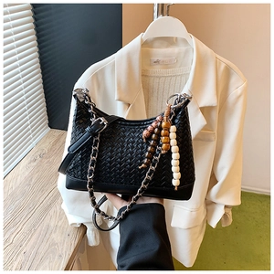 Detail of black woven crescent bag with wood bead charm and silver chain strap