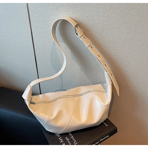 Detail of adjustable leather shoulder strap and silver buckle on cream dumpling bag