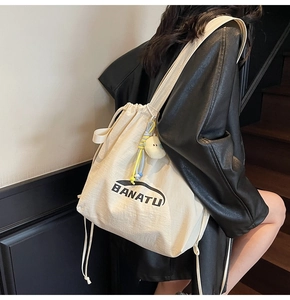 Detail eines cremefarbenen Segeltuch-Rucksacks mit BANATU-Logo und Küken-Anhänger