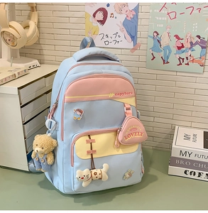 Close-up of blue student backpack with cartoon charms and pink coin purse detail