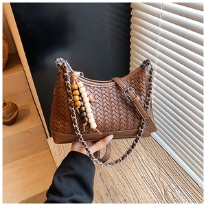 Detail of a brown woven texture bag featuring a metal chain and wood bead charm