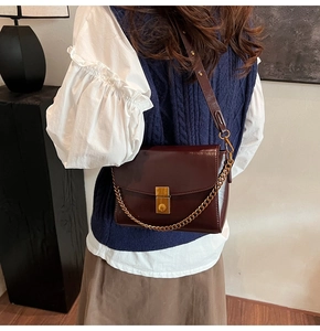 Détail du sac à bandoulière en cuir brillant bordeaux avec chaîne dorée et boucle métal