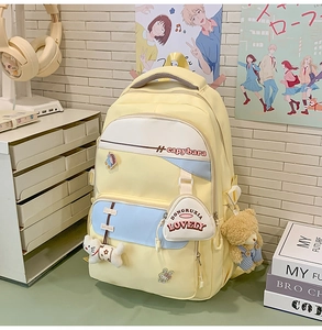Close-up of yellow nylon backpack with cartoon badges, plush charms and lovely pocket