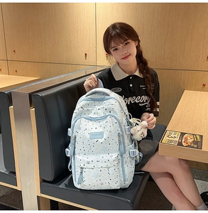 Detail of light blue backpack with star patterns and multiple storage pockets in a cafe