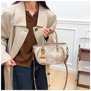 Detail view of the champagne velvet bucket bag showing glossy texture and golden hardware