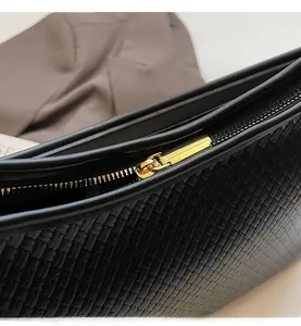 Détail du zip doré fluide sur la texture tissée noire d'un sac cabas contemporain chic