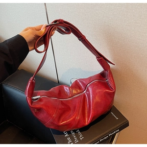 Detail view of burgundy crescent bag with textured paneling and silver zipper closure