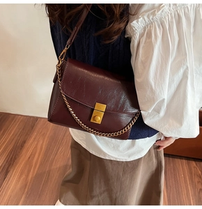 Détail du sac bandoulière marron foncé vintage avec chaîne dorée et boucle carrée