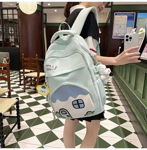 Outdoor shot of a mint green student backpack with cartoon print and plush pendants