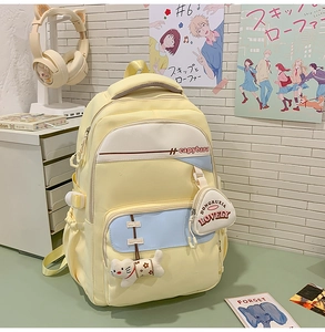 Detail of light yellow school backpack with blue accents and cute cat plush charm