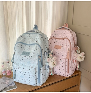 Detail of blue and pink star pattern backpacks with plush bear charms and side buckles
