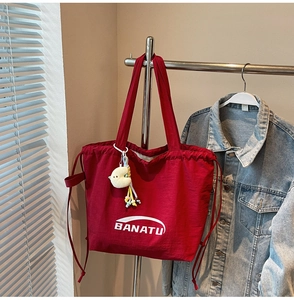 Detailansicht einer großen roten Nylontasche mit Kordelzug und Plüsch-Anhänger