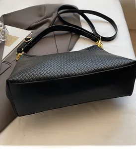 Détail du sac à bandoulière tressé noir avec ferrures dorées et base en cuir lisse