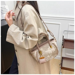 Detail view of the velvet bucket bag featuring leather handles and gold metal hardware