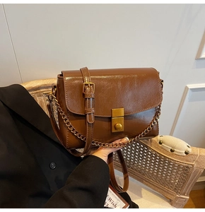Détail d'un sac bandoulière vintage en cuir verni marron avec plissée et chaîne