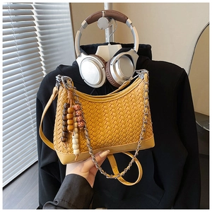 Detail of yellow woven faux leather bag with wooden beads and metal chain strap