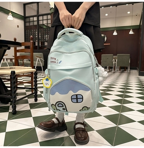Close-up of mint blue student backpack with cute house pattern and yellow cloud charm