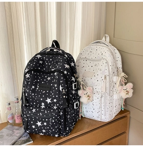 Detail of black and white star print backpacks with cute plush bear charms and side buckles
