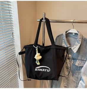 Detail der schwarzen Nylon-Tasche mit BANATU-Logo und gelbem Mond-Plüschanhänger