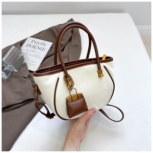 Close-up of contrast stitching on a cream bucket bag with a miniature bag charm