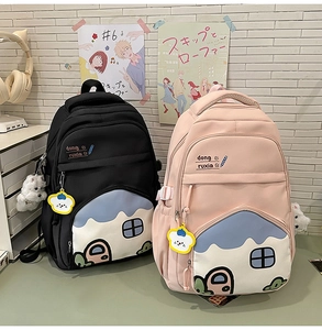 Detail of cute school backpacks in black and pink with puppy plush charms and thick straps