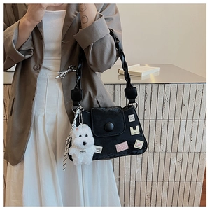 Detalle de bolso de hombro negro con pegatinas bonitas y colgante de cachorro peluche