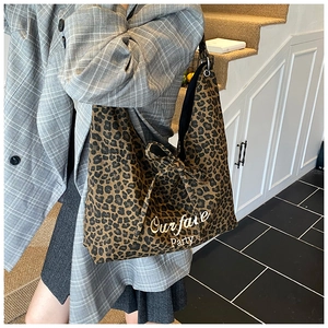 Détail du sac cabas léopard avec texte blanc et ruban à nœud noir sur une bandoulière