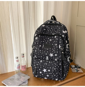 Detail view of large-capacity backpack with star print and side buckles on wooden desk
