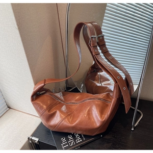 Detail of adjustable wide shoulder strap with silver metal buckles on brown hobo bag