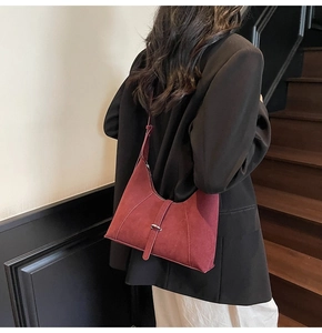 Model wearing a wine red suede hobo bag over the shoulder with a black blazer
