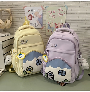 Detail of cute school backpack with creative block house patterns and plush pendants