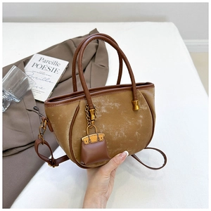 Detail of vintage brown leather bucket bag with mini charm and gold metal hardware