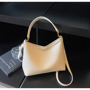 Détail du sac cabas matelassé beige avec ferrures dorées sur une étagère élégante