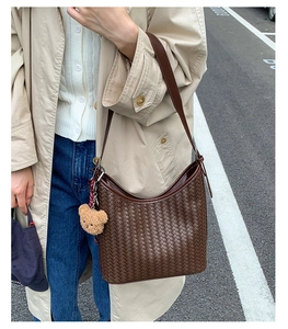 Close-up of deep brown woven leather hobo bag with a cute bear charm in natural light