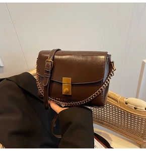 Détail du sac en similicuir marron foncé avec chaîne dorée et fermoir métallique carré